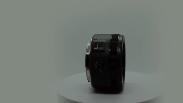 Vista lateral de una lente retrato de 50mm STM EF lente giratoria 360 grados aislada en fondo gris — Vídeos de Stock