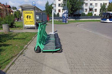 Krakow, Polonya - 05 Mayıs 2021: Bolt şirketinden yeşil elektrikli scooter 'lar gün içinde otobüs durağının karşısındaki kentte park halinde..