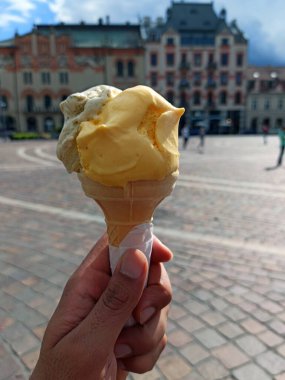 Krakow, Polonya, Avrupa 'nın merkezindeki Avrupa binasının önünde lezzetli görünümlü bir Saffron ve kahveli dondurma külahının el ele tutuşması. Yaz boyunca seyahat kavramı