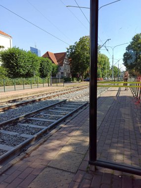 Gdansk, Kuzey Polonya - 14 Ağustos 2020: Ya bir tramvay istasyonunun içinden bakın ya da raylara karşı durun ve uçağa binmeyi bekleyen bir yolcu.