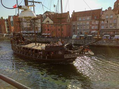 GDANSK, POLAND - 10 Ağustos 2020: Gdansk 'taki Motlawa nehrinde turist taşıyan korsan gemisi. Gdansk 'taki vinç şehrin sembolü ve Avrupa' da hayatta kalan en eski vinç olarak inşa edildi.