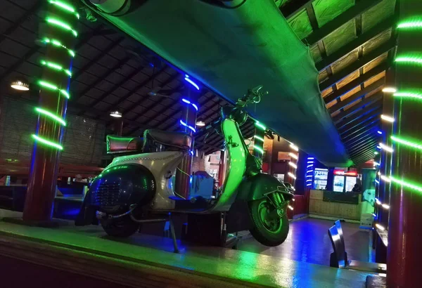 ヴィンテージレトロ2輪モータースクーター匿名のインドのレストランでカラフルなライトに対して屋内駐車 — ストック写真