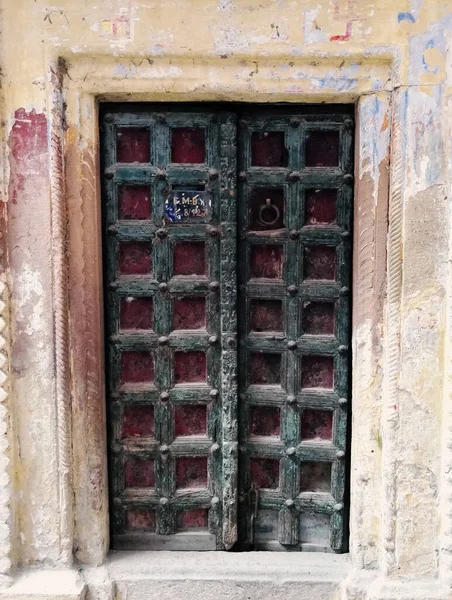 インドのバラナシのカラフルな家の間の狭い路地にある地元の住居の正方形のパターンのデザインの装飾的な暗い色の扉 — ストック写真