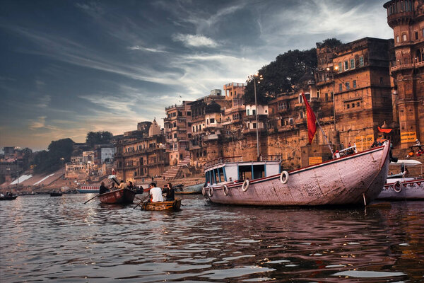 Varanasi, India - November 01, 2016: Dramatic sunset in a holy hindu place of worship with lots of tourists on boats and ancient architecture ghat located in Uttar pradesh.