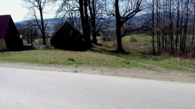 Limanowa, Güney Polonya - 01 Nisan 2021: Polonya dağlarındaki Lysa Gora beskid wyspowy 'de terk edilmiş ev ve ağaçlara karşı boş bir yol gösteren köy manzarası