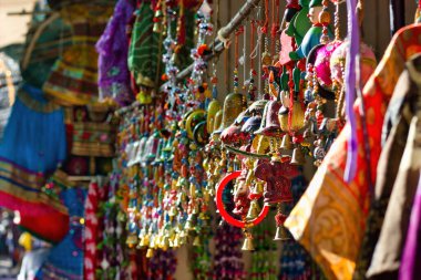 Rajasthan eyaletinin ticari caddesinde satılık olarak asılı renkli dekoratif eşyalar sergileniyor.