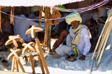 Pushkar, Hindistan - 10 Kasım 2016: Rajasthani türbanlı bir adam deve satışı yapıyor Pushkar fuarı veya Rajasthan eyaletindeki bir ticaret pazarında ahşap eşyalar.