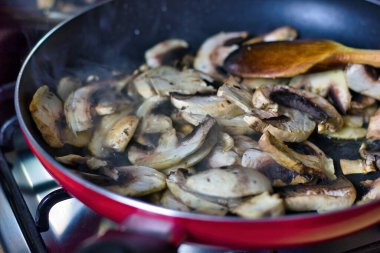 Taze kesilmiş mantarın üst görüntüsü tavada pişiyor ve buhar ev yemeği vegan konseptini gösteriyor.