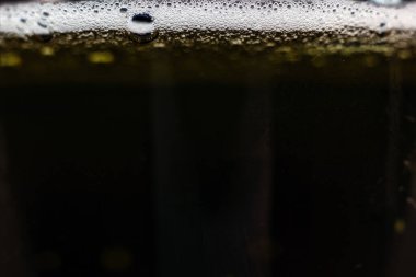 Kenarlarında köpük ve köpüklerle yakın plan koyu bira..