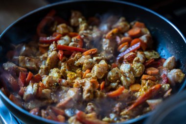 Sebze yahnisi, sebzeli tavuk pişirme. Yemek pişirme süreci. İndüksiyon ocağında sebzeli tava ve tavuk eti, buharlı baharatlı baharatlı zerdeçal Hint mutfağı.