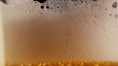 Ekstrem makro görüntüler, şeffaf bir baloncuk oluşum döngüsünün içinden geçer ve soğuk, altın renkli biranın içinde, bardaktan boşalırcasına patlar. Alkollü içecek içindeki soyut doku.
