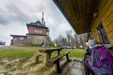 Wielki Lubon, Polonya - 15 Temmuz 2021: İnsanlar Beskid Wyspowy bölgesinde yer alan bir Polonya dağının zirvesinde yağmurlu havada yağmurlukla sıcak içecekler içmeyi seviyorlar