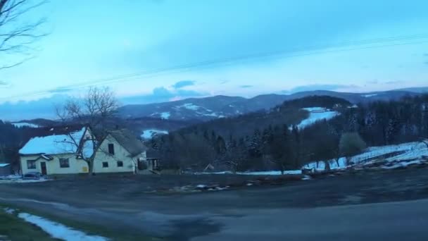 从一辆行驶中的汽车通过侧窗俯瞰波兰山景 冬季房屋被白雪环绕在山丘上的景象 — 图库视频影像