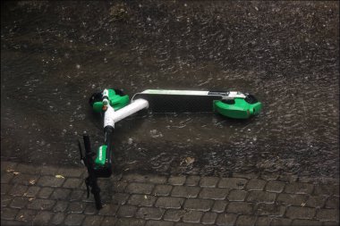 Bir elektrikli scooter terk edildi ve şiddetli bir yağmur seli konseptine takıldı..