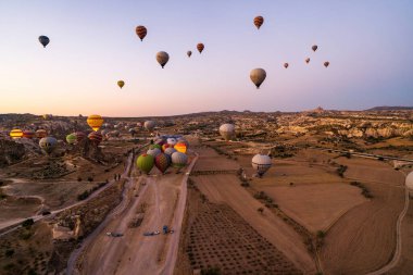 Kapadokya, Türkiye - 14 Eylül 2021: Goreme 'de sabahın erken saatlerinde gökyüzünde yüzen renkli sıcak hava balonlarının geniş açılı görüntüsü