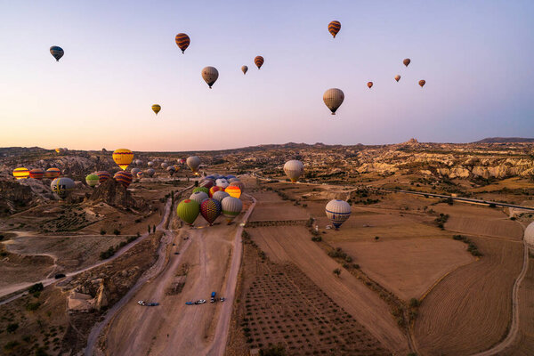 Cappadocia, Turkey - September 14, 2021: Wide angle aerial shot of colorful hot air balloons together floating in the sky at early morning in Goreme