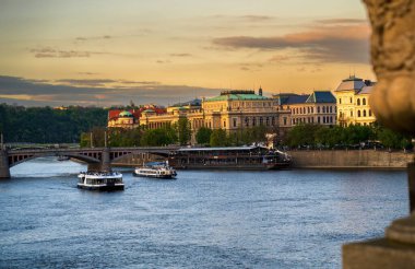 Prag Vltava Nehri tekneleri ve Ulusal Tiyatro ile altın saat günbatımında, tarihi Prag kıyısı klasik mimari ile, Çek Cumhuriyeti