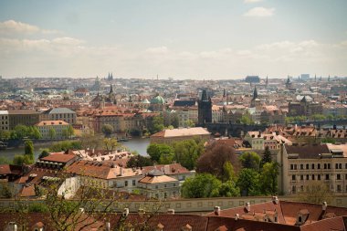 Prag şehir manzarası manzarası Vltava Nehri, kırmızı çatılar, tarihi binalar ve bulutlu gökyüzü altında katedral kuleleri