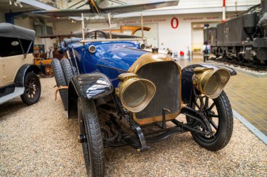 Prag, Çek Cumhuriyeti - 1 Mayıs 2023: Müze ortamında pirinç radyatör, pirinç farlar ve çarpıcı mavi bir gövdenin yer aldığı el değmemiş bir klasik otomobil. Otomotiv geçmişi için ideal