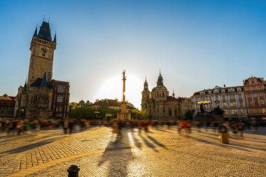 Tarihi saat kulesi, katedral ve anıtı olan hareketli, güneşli bir Prag meydanı. Bulanık kalabalık kaldırım taşı plazasında ilerleyip zamansız mimariyi ve canlı şehir yaşamını yakalıyor.