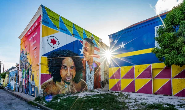 Mavi ceketli bir adam ve dağların arkasında sarı bir bayrak.