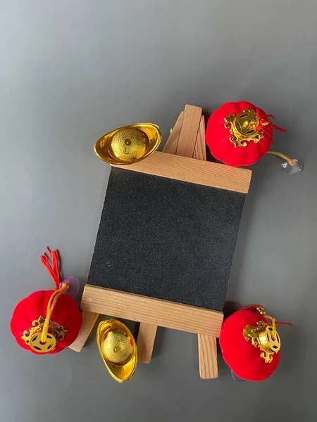 Chinese New Year sale or promo template. Red lanterns and gold ingot with blackboard on grey background. Chinese characters on gold ingot means prosperity