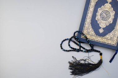 Ramazan Kareem, Bayram Mübarek veya İslami kavram. İslami kutsal kitap, Kuran ya da Kuran, gri arka planda tespih ya da tasbih ile. Kitabın üzerindeki Arapça kelimeler kutsal Kur 'an anlamına gelir..