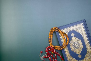 Ramazan Kareem, Bayram Mübarek veya İslami kavram. İslami kutsal kitap, Kuran ya da Kuran, gri arka planda tespih ya da tasbih ile. Kitabın üzerindeki Arapça kelimeler kutsal Kur 'an anlamına gelir..