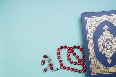 Ramazan Kareem, Bayram Mübarek veya İslami kavram. İslami kutsal kitap, Kuran ya da Kuran, gri arka planda tespih ya da tasbih ile. Kitabın üzerindeki Arapça kelimeler kutsal Kur 'an anlamına gelir..