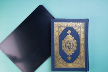 Teknoloji cihazlarının ve uygulamaların Kuran 'ı dijitalleştirmeye veya e-Kuran' a uygulanması. Çevrimiçi öğrenme ya da uygulamaları kullanarak Kur 'an resitali. Kitabın üzerindeki Arapça kelimeler kutsal Kur 'an anlamına gelir.