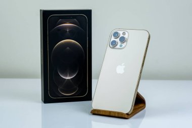 iPhone 12 Pro Max Gold kutusunun yanında bir müşteri tarafından tutuluyor.