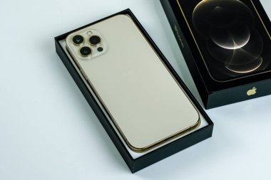 iPhone 12 Pro Max Gold kutusunun yanında bir müşteri tarafından tutuluyor.