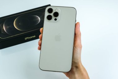iPhone 12 Pro Max Gold kutusunun yanında bir müşteri tarafından tutuluyor.