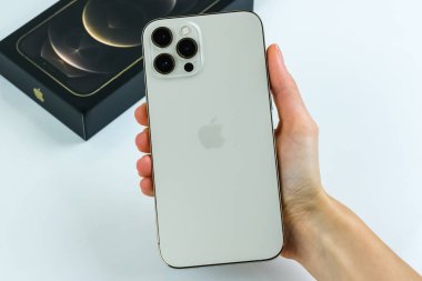iPhone 12 Pro Max Gold kutusunun yanında bir müşteri tarafından tutuluyor.