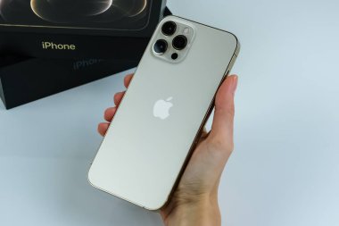 iPhone 12 Pro Max Gold kutusunun yanında bir müşteri tarafından tutuluyor.
