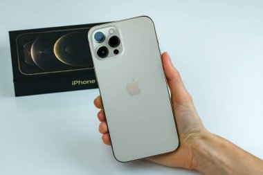 iPhone 12 Pro Max Gold kutusunun yanında bir müşteri tarafından tutuluyor.