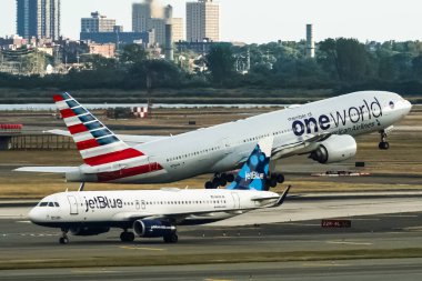 American Airlines Boeing 777, arkasında Blue Airbus A320 ile John F. Kennedy Uluslararası Havalimanı 'ndan kalkıyor. Queens, New York