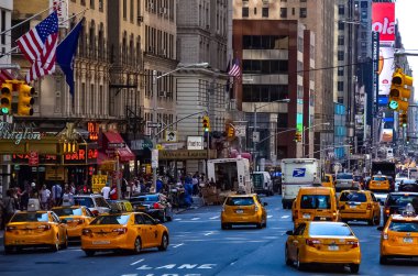 Times Meydanı 'nda güzel bir yaz günü, sarı New York taksileri renkli reklam panolarının içinden geçiyor. Manhattan, New York.