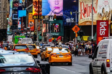 Times Meydanı 'nda güzel bir yaz günü, sarı New York taksileri renkli reklam panolarının içinden geçiyor. Manhattan, New York.