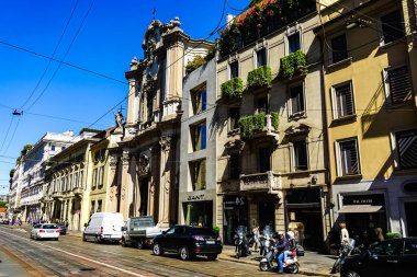 Milan, İtalya 'da güneşli bir günde Milan tramvayı, yayalar ve arabalarla dolu bir panorama.