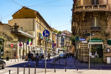 Milano sokak panoramasında güneşli bir günde Milan tramvayları, yayalar ve arabalar.