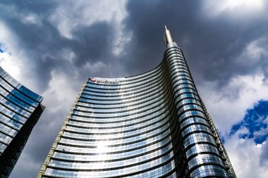 Milano sokak panoramasında güneşli bir günde Milan tramvayları, yayalar ve arabalar.