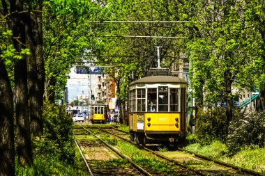 Milan, İtalya 'da güneşli bir günde Milan tramvayı, yayalar ve arabalarla dolu bir panorama