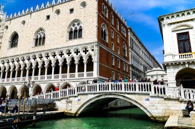 Venedik 'te yüzen Gondolalar ve turistler Riva degli Schiavoni rıhtımında arka planda The Doge' s Palace ile güzel bir günün tadını çıkarıyorlar.. 