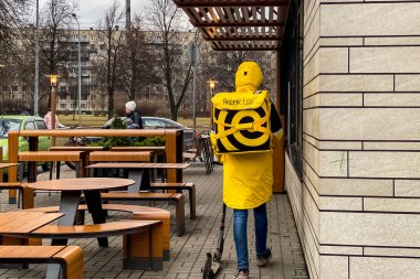 Yandex.Eats man from the food delivery service Yandex Eats, on the streets of Saint Petersburg, Russia. clipart