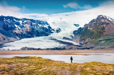 Vatnajokull buzulundan eriyen buz. Güneşli yaz manzarası, sahilde yürüyen bir adam, Vatnajokull Ulusal Parkı, İzlanda, Avrupa. İşlenmiş fotoğraf sonrası sanatsal stil.
