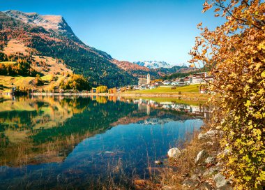Resia köyünün ve gölün muhteşem sonbahar manzarası. İtalyan Alpleri, Güney Tyrol, İtalya, Avrupa 'nın muhteşem sabah manzarası. Seyahat konsepti arka planı.