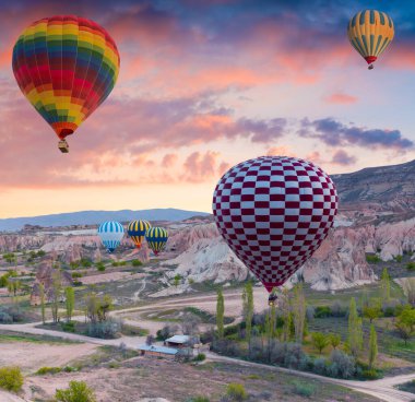 Sabahın erken saatlerinde Cappadocia 'da balonlarla uçmak. Kırmızı Gül Vadisi, Goreme Köyü, Türkiye, Asya 'da renkli gündoğumu. İşlenmiş fotoğraf sonrası sanatsal stil.