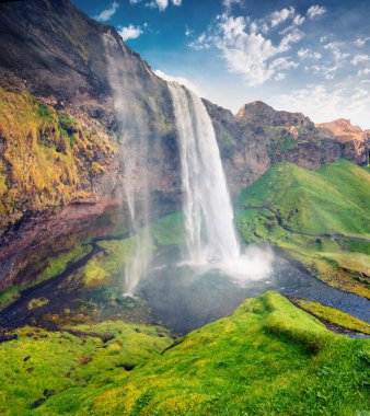 Seljalandfoss Şelalesi 'nin yazın Seljalandsa nehri üzerindeki muhteşem sabah manzarası. İzlanda, Avrupa 'da renkli bir açık hava sahnesi. İşlenmiş fotoğraf sonrası sanatsal stil.