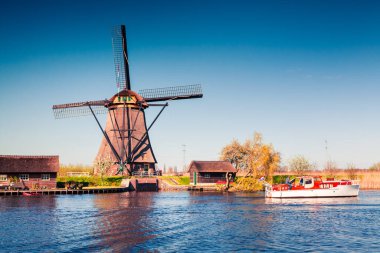 Hollanda 'daki Kinderdijk Müzesi' nin ünlü yel değirmenleri. Kırsal kesimde güneşli bir bahar sabahı. Hollanda, Avrupa 'da renkli bir açık hava sahnesi. UNESCO Dünya Mirası Alanı. İşlenmiş fotoğraf sonrası sanatsal stil.